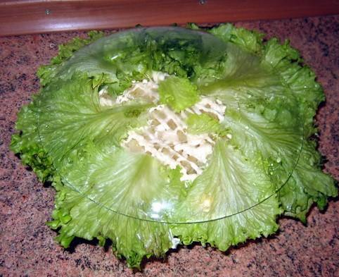 Аккуратно устилаем кастрюлю с салатом по периметру салатными листьями и накрываю стеклянным блюдом